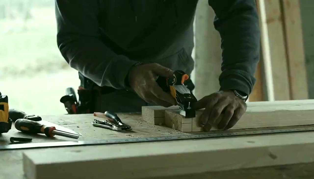 A tradesperson measuring on a job site, tools laid out in natural light.