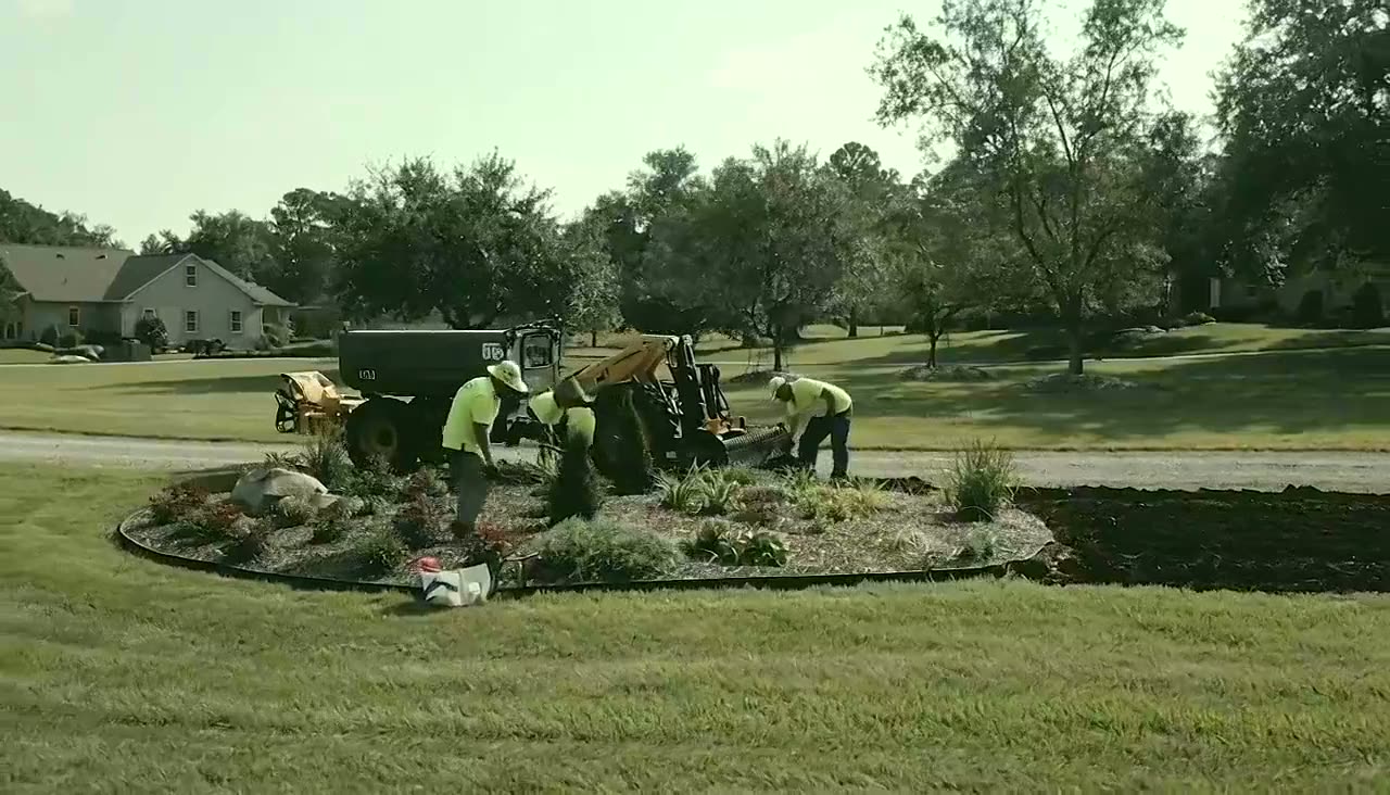 A commercial landscaping crew working with equipment in daylight.