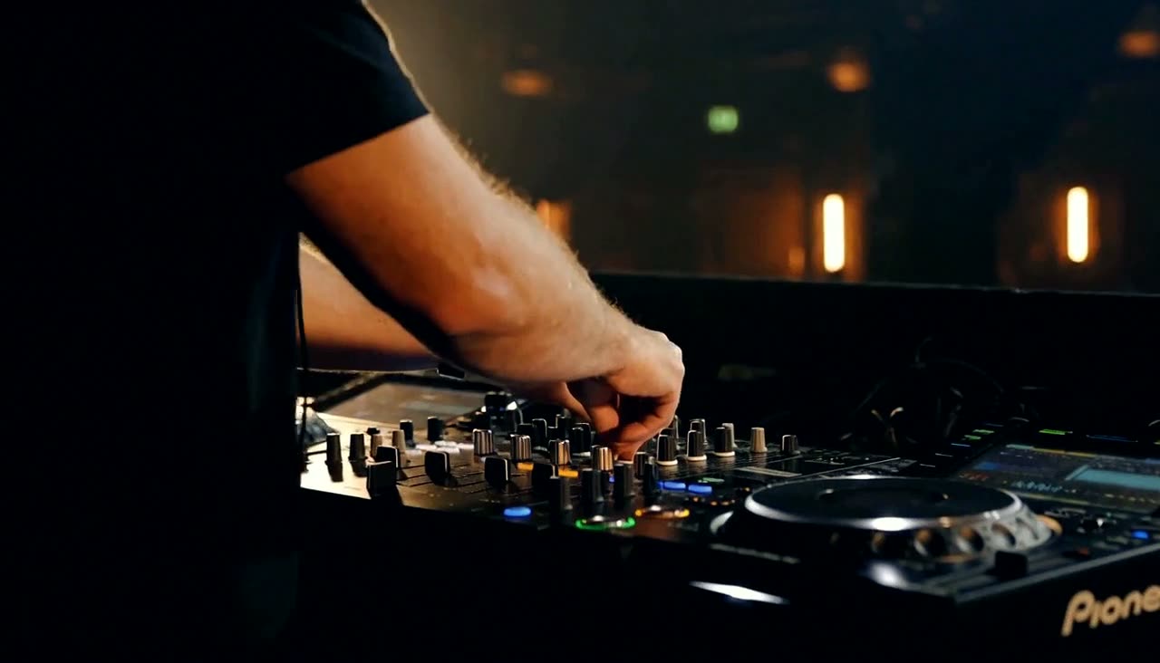 A DJ working a mixer in a dim venue before doors open.