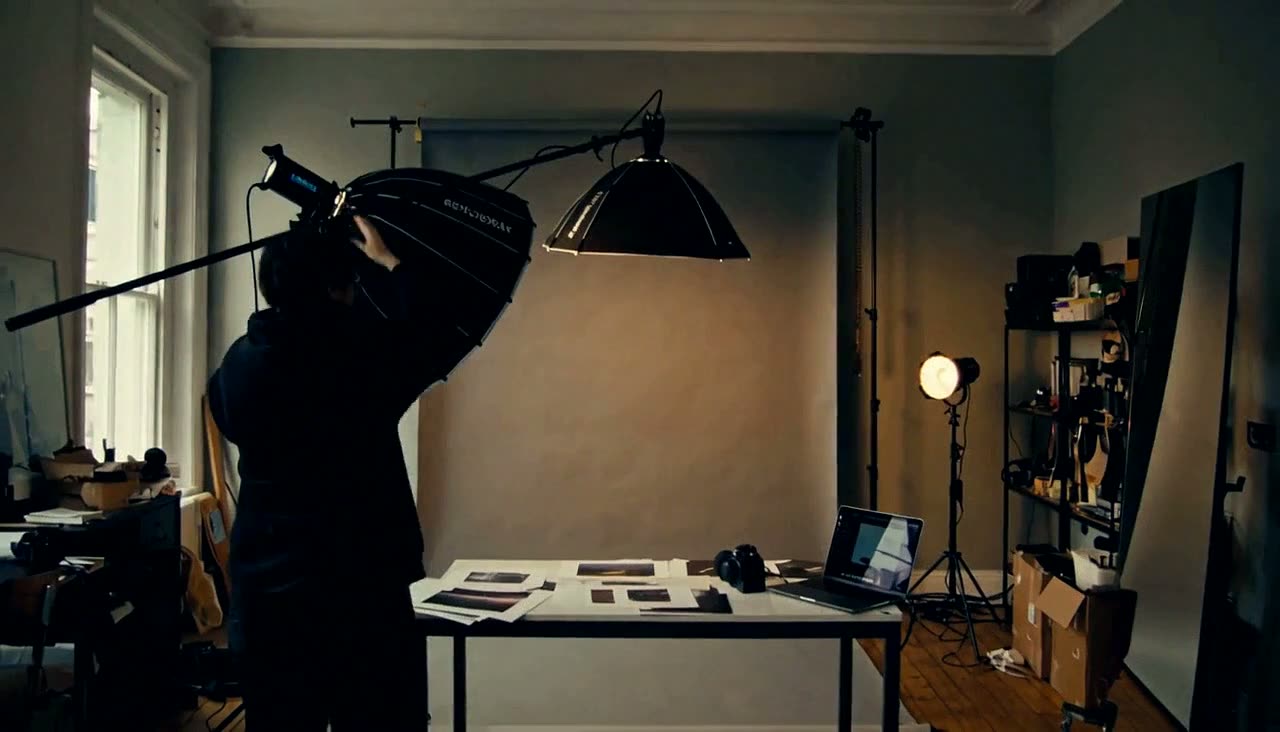A photographer moving between lights in a working studio.